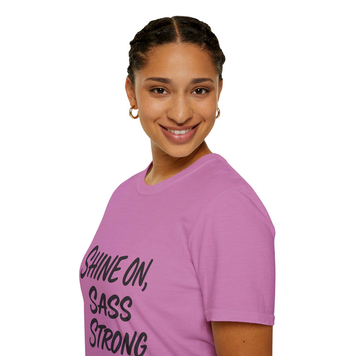 Female model wearing a pink t-shirt with 'Shine on, Sass Strong' text 