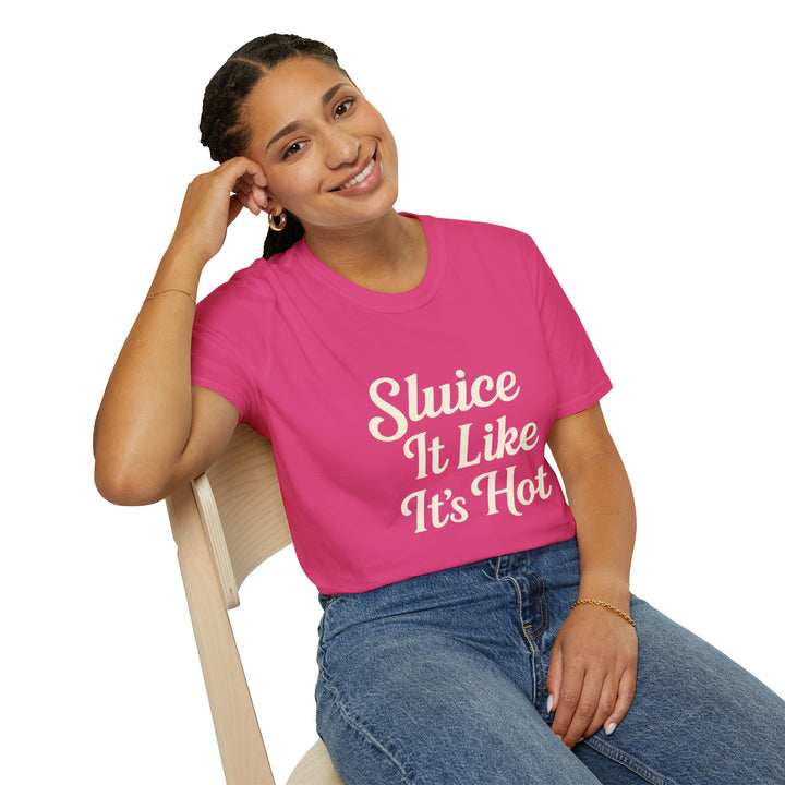 Female model wearing a pink t-shirt with 'Sluice It Like It's Hot' text, sitting on a chair.